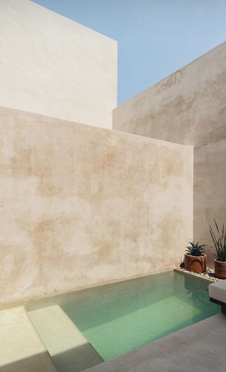 Non-Slip Microcement Flooring Pool Deck in Jeddah Textured beige sand-colored paving with a matte finish surrounding a teal swimming pool, seamless Microcement Floor installation by Floroz KSA.