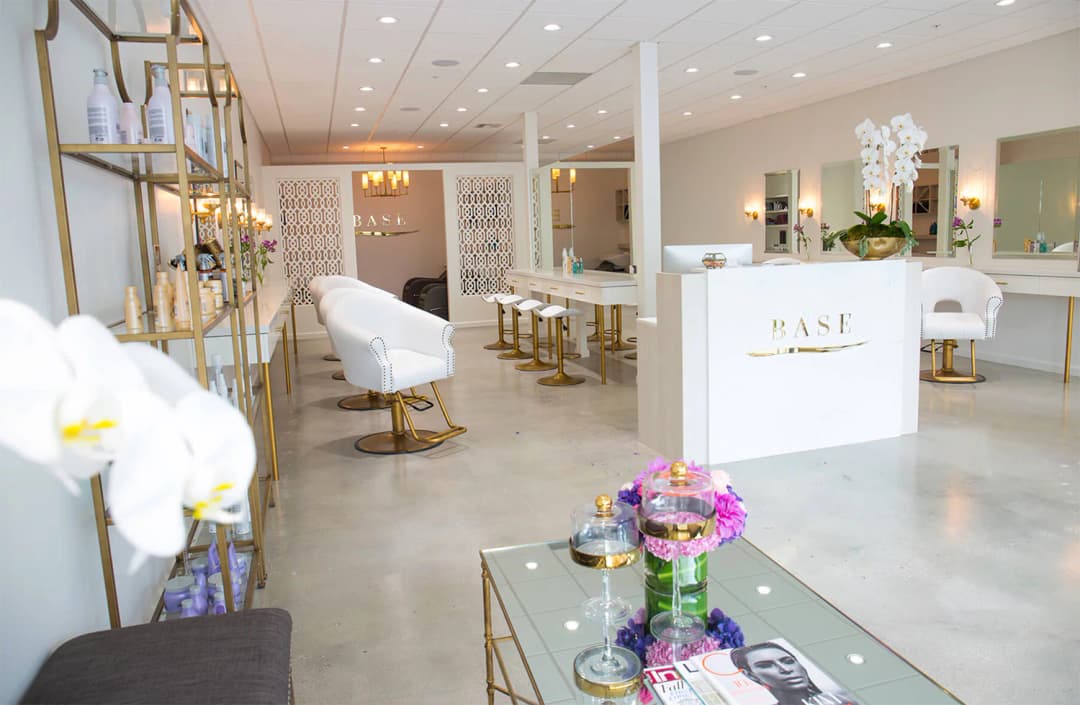 Chemical-Resistant Microcement Flooring for Salons in Riyadh Modern luxury salon in Riyadh with seamless light grey microcement flooring, white chairs, and gold accents.